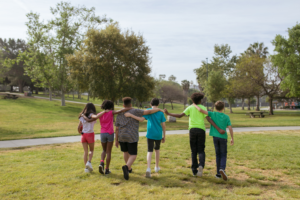 Stock photo of children walking in a park with their arms around each others' shoulders
