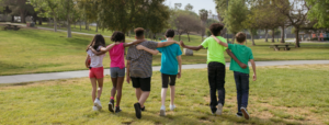 Stock photo of children walking in a park with their arms around each others' shoulders