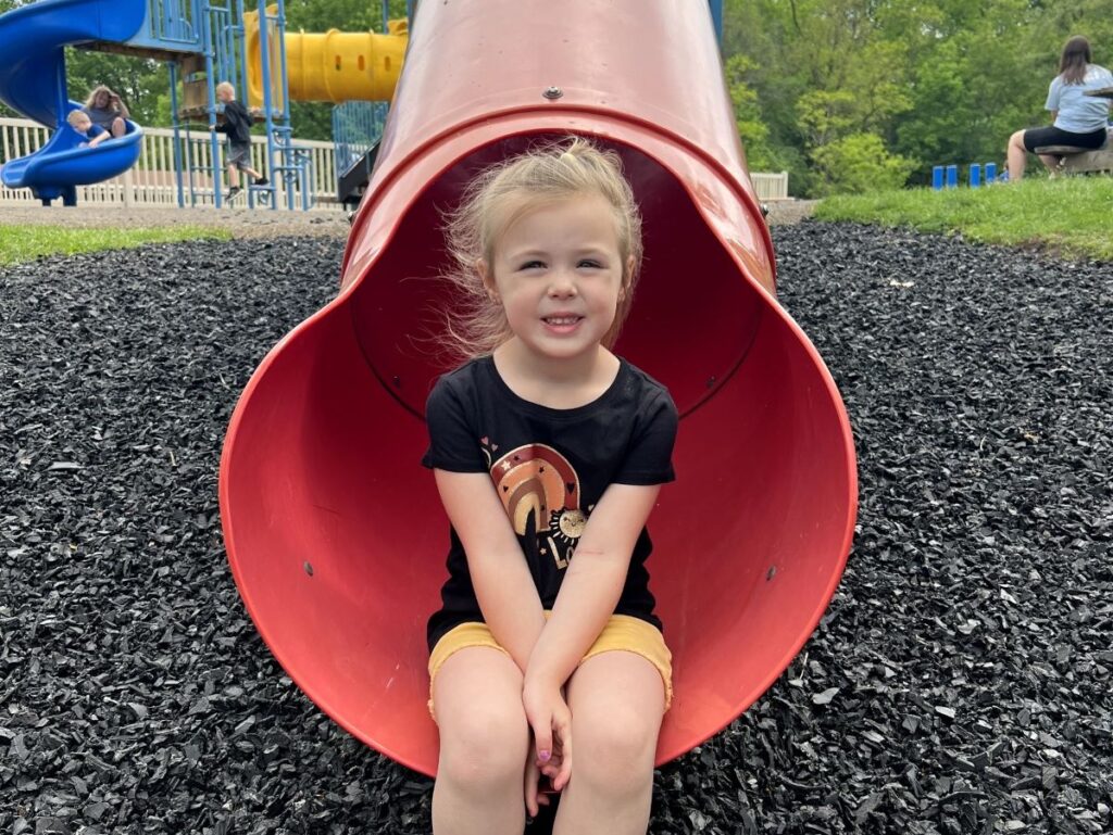 A young girl sitting on the slide at Mt. Nazareth Learning Center
