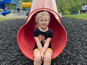 A young girl sitting on the slide at Mt. Nazareth Learning Center