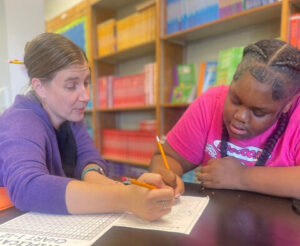 A teacher and a student work together on a multiplication problem.