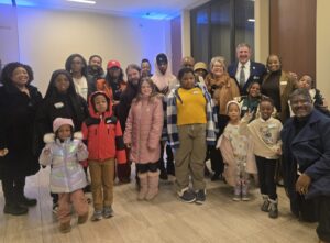 A photo of a group smiling at the camera. There are numerous adults and children of varying ages, including Chris Brussalis, President of Point Park University.