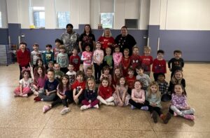 Teachers and children from a daycare center are gathered in a group smiling at the camera.